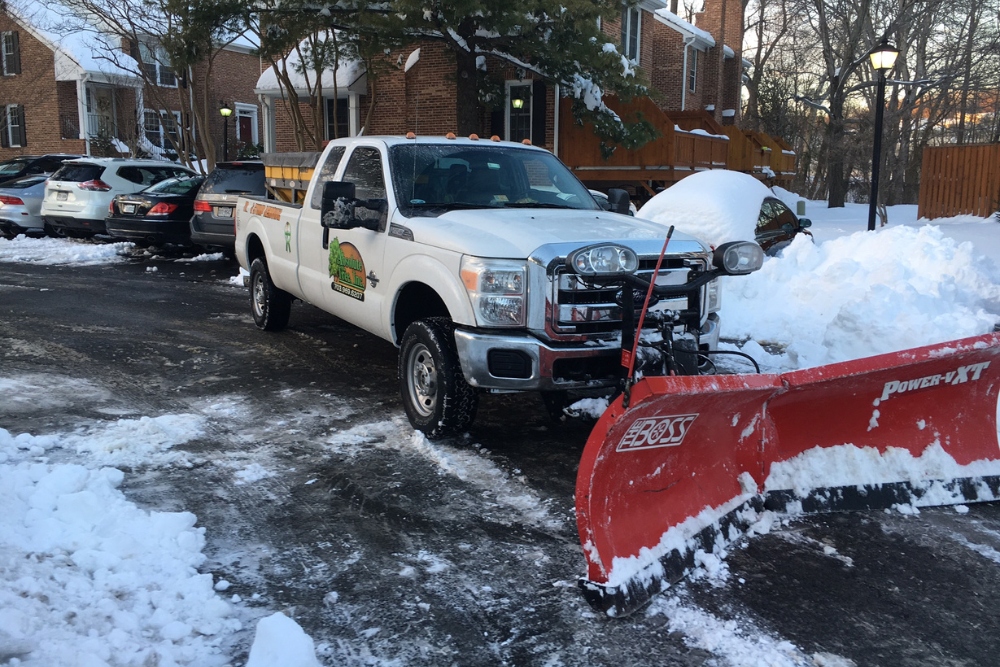 An Absolute Tree Service truck with snow plow providing commercial snow removal services in Northern Virginia HOA community.